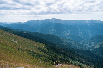 Fototapeta na wymiar Alpine Meadows Trail, Krasnaya Polyana Resort. Alpine Meadows Walking Route. Aerial view of the green mountain valley, surrounded by high mountains.