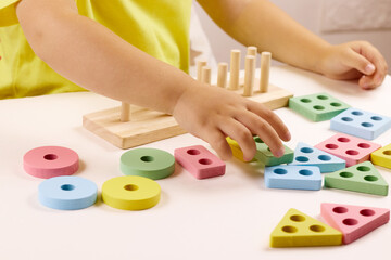 The child plays with colorful toy blocks. eco wooden toys. Little smart child playing natural toys....