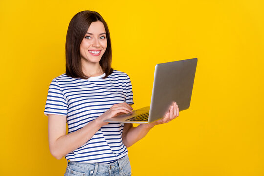 Photo of nice young woman hold laptop video online conference smiling dressed trendy striped look isolated on yellow color background