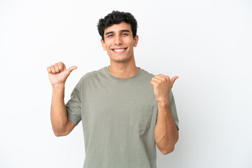 Young Argentinian man isolated on white background pointing to the side to present a product