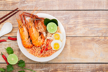 Tom Yum Goong Instant Noodle Ramen - Asian Style Thai and Chinese are spicy. Placed on a wooden table, seafood shrimp, lime, red chili, garlic, galangal, lemongrass, kaffir lime stand original,