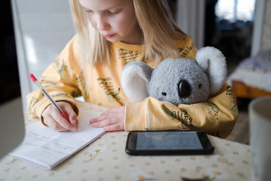 Midsection Of Girl Writing On Notebook And Using Tablet