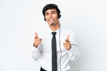 Telemarketer man working with a headset isolated on white background pointing to the front and...