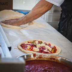Italian pizza chef preparing and cooking pizza with mozzarella cheese tomato sauce and fresh basil leaf