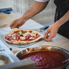 Italian pizza chef preparing and cooking pizza with mozzarella cheese tomato sauce and fresh basil leaf