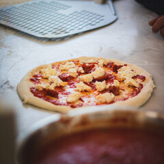 Italian pizza chef preparing and cooking pizza with mozzarella cheese tomato sauce and fresh basil leaf