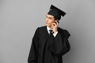 Young Argentinian university graduate isolated on grey background keeping a conversation with the mobile phone with someone