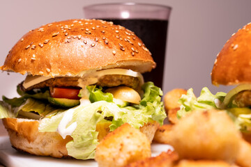 Burger with beef and vegetables, soda in the background, close-up