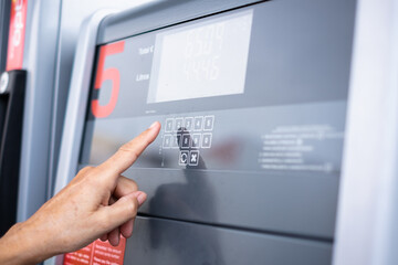 Woman at self-service fuel pump in European gas station types on the display the required amount - inflation, price increase, economy, speculation concept