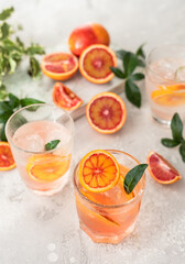 Hard seltzer cocktail with blood orange. Cocktail or lemonade with fresh citrus. Refreshing drinks, low alcohol mocktail. Party concept. Shadow and sunlight.