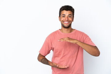Young handsome Brazilian man isolated on white background holding copyspace imaginary on the palm...