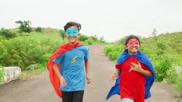 Tracking shot of excited happy running teenager kids in super hero costume on empty road - concept of fantasy, teamwork and courage.