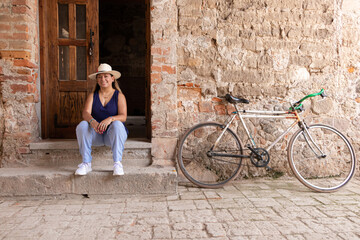 Fototapeta na wymiar Latina morena sentada en la puerta junto a una bicicleta