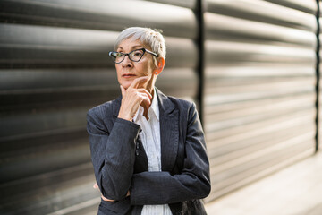 Outdoor portrait of pensive senior businesswoman in front of company building. 