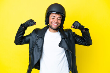 Young Brazilian man with a motorcycle helmet isolated on yellow background doing strong gesture