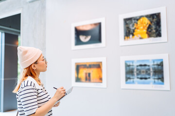 Fototapeta na wymiar Woman visiting art gallery her looking pictures on wall watching photo frame painting at artwork museum people lifestyle concept.