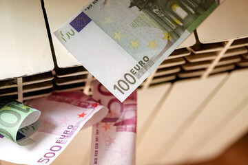 Euro banknotes in a central heating radiator, the concept of expensive heating costs in energy crisis