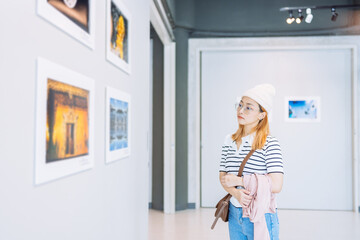 Woman visiting art gallery her looking pictures on wall watching photo frame painting at artwork museum people lifestyle concept. - obrazy, fototapety, plakaty