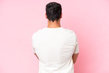 Young caucasian man isolated on pink background in back position