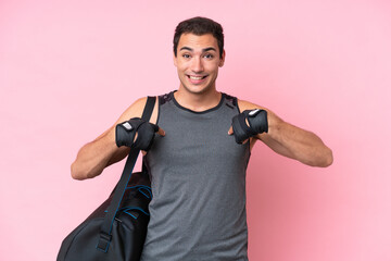 Young sport caucasian man with sport bag isolated on pink background with surprise facial expression