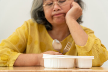 Unhappy Asian senior woman anorexia and say no to ready meals, Elderly home alone and bored food...