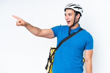 Young caucasian man with thermal backpack isolated on white background pointing away