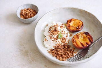 Summer dessert. Organic grilled peaches served with stracciatella cheese and caramelized nuts crumb on white background. Selective focus