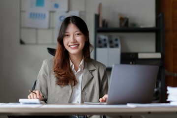 Asian Business Woman or Accountant do math and analyze with calculator and paperwork on desk, account, audit and saving concept