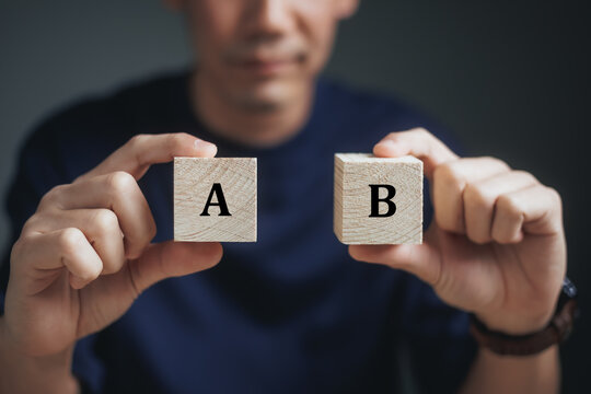 Business Choices For Difficult Situations, A or B, man holding two wooden cubes with A or B word on it, making decision.