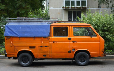 An orange cargo minibus is parked in the courtyard of a residential building, Prospekt, Bolshevikov, St. Petersburg, Russia, September 2022