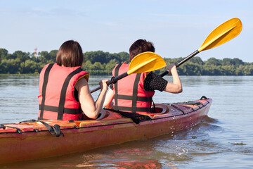 Two active women, best friends kayaking in Danube river at summer morning. Kayaking, travel, leisure concept