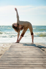 Young woman doing yoga outdoor near sea, relax lifestyle