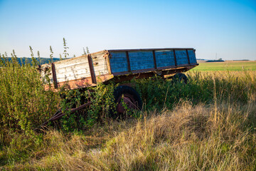 Fototapeta na wymiar Old farmers trailer overgrown with vegetation in autumn
