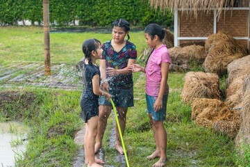 Happy child girl playing in large wet mud and dirt in rainy season