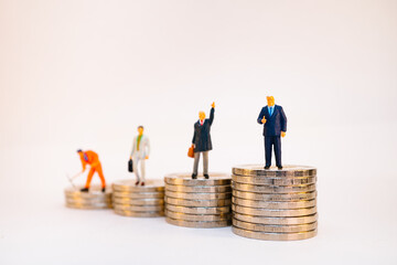 Miniature people, group of businessman standing on stack coins using as business and financial...