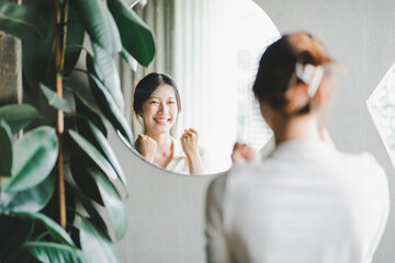 Asian woman looking through the mirror and confident of herself. cheer yourself up - obrazy, fototapety, plakaty