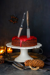 Moist chocolate cake with red bloody icing and two knives. Spider in the background, halloween mood...