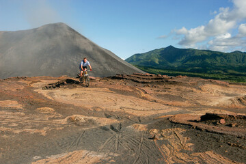 Western tourist riding a mountain bike on Yasur Volcano, Tanna Island, Vanuatu