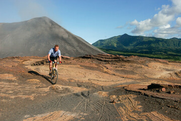 Fototapeta premium Western tourist riding a mountain bike on Yasur Volcano, Tanna Island, Vanuatu