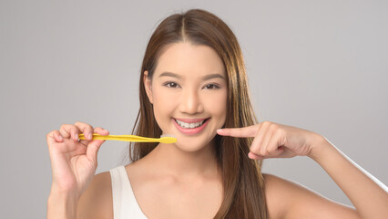 Young smiling woman holding toothbrush over white background studio, dental healthcare and Orthodontic concept..