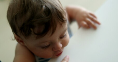 Cute baby toddler learning to stand holding into parent leg, infant one year old development leaning with hand