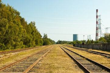 Fototapeta na wymiar railway, in the photo straight lines of railway tracks in the background of the power plant tower and blue sky
