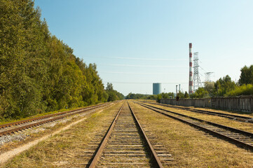 Fototapeta na wymiar railway, in the photo straight lines of railway tracks in the background of the power plant tower and blue sky