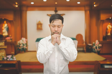 Asian man beard wearing whith shirt christian praying for blessings from god within the church...