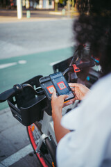 Perspective shot of a woman scanning a qr code with phone to rent an electric bike in the city.