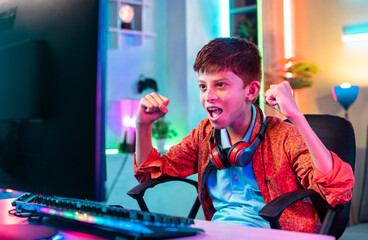 shouting teenager kid celebrating win by shouting while playing online video game on computer at home - concept of challenge, gaming addiction and entertainment.
