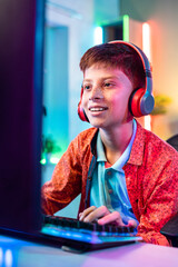 Vertical shot, Happy smiling teenager kid playing live video game on computer by talking on wireless headset at home - concept of entertainment, technology addiction and cyberspace © WESTOCK