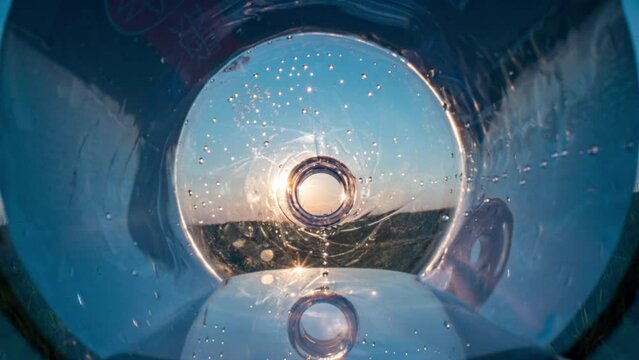 world's plastic pollution crisis. plastic trash in ocean. plastic garbage in nature, camera movement through a bottle in a beautiful landscape, sunset, plastic garbage lies on a meadow, litter