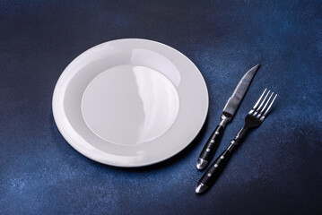 Empty white plate on blue background table. Flat lay