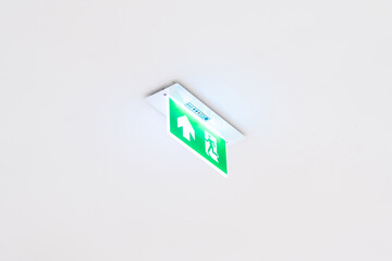 White neon sign depicting a fire exit with green background hangs from the ceiling.